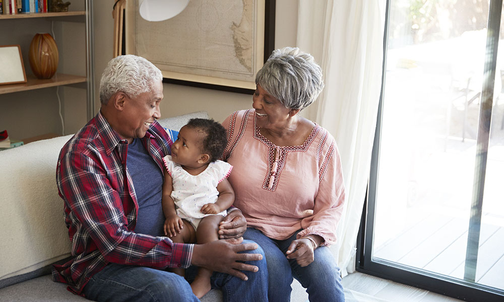 Life Insurance - Portrait of Cheerful Grandparents Sitting on the Sofa with Their Baby Granddaughter.jpg