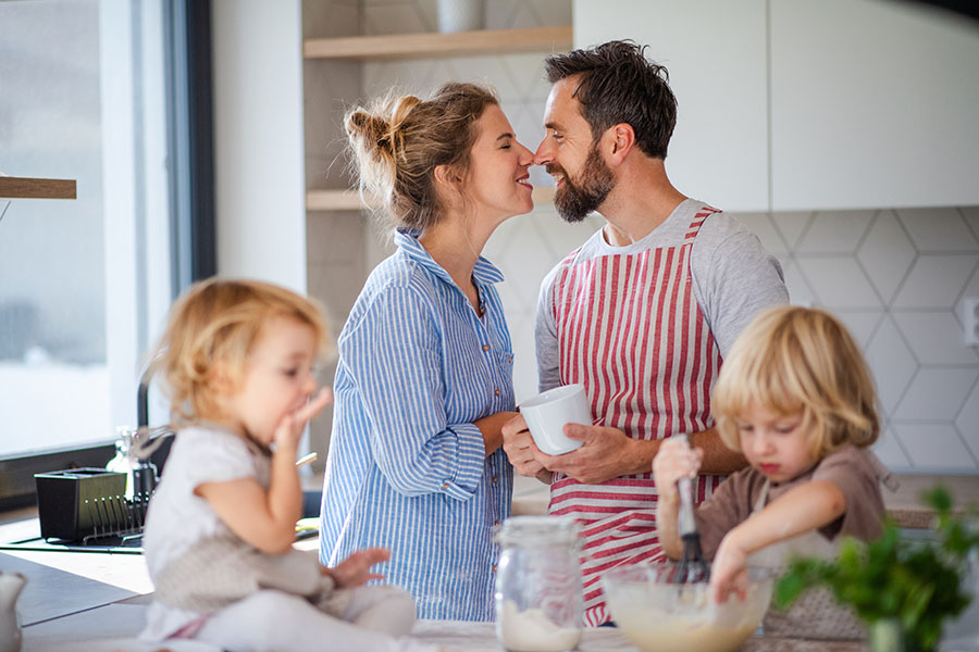 Personal Insurance - Smiling Mother and Father Standing in the Kitchen Having Fun Baking With Their Young Kids